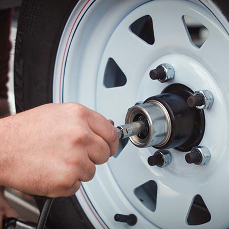 A close-up photo of a hand performing maintenance on a tire rim.