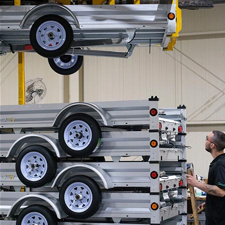 A person watches as trailers are machine-stacked for shipping.